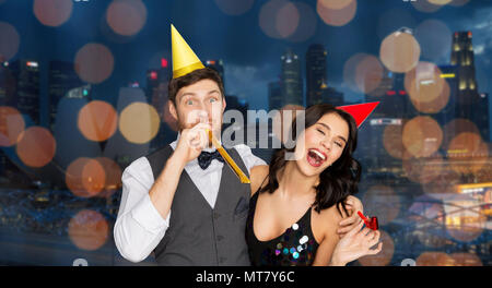 Coppia felice con party soffianti divertendosi Foto Stock