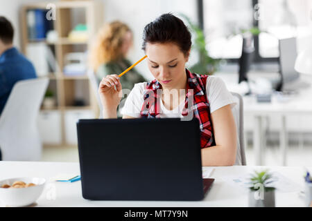 Donna creativa con computer portatile in ufficio Foto Stock