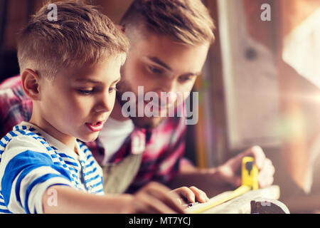 Padre e Figlio con il righello di legno di misura in officina Foto Stock