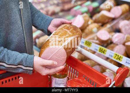 Acquirente con salsiccia con un paniere di generi alimentari in negozio Foto Stock