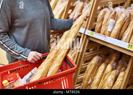 Acquirente con pane baguette con un paniere di generi alimentari in negozio Foto Stock