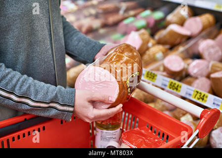 Acquirente con salsiccia con un paniere di generi alimentari in negozio Foto Stock