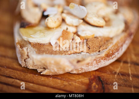 Primo piano di un delizioso faccia aperta sandwich con burro di arachidi, noci di acagiù e una varietà di altri ingredienti su una tavola di legno Foto Stock