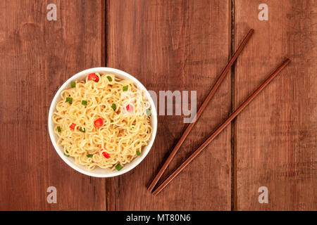 Una foto aerea di una ciotola di tagliolini con bacchette e copia di spazio, al buio su un rustico texture di sfondo Foto Stock