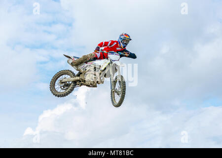 Racer su un motociclo in volo, salti e prende il largo su un trampolino di lancio verso il cielo. Foto Stock