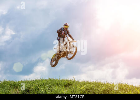 Racer su un motociclo in volo, salti e prende il largo su un trampolino di lancio verso il cielo. Foto Stock