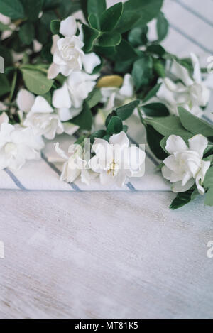 Cape fiori di gelsomino con striscia blu tovagliolo bianco sul tavolo di legno Foto Stock