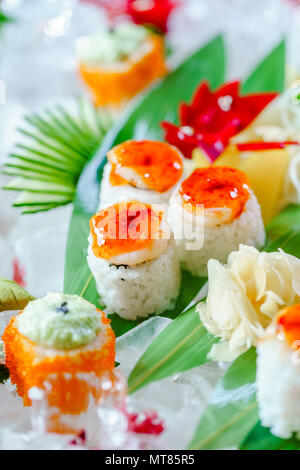 Un sacco di sushi rotoli con vari ripieni. Colpo di cotto giapponese classico cibo servito su ghiaccio. Immagine di sfondo Foto Stock