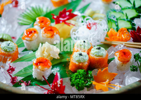 Un sacco di sushi rotoli con vari ripieni. Colpo di cotto giapponese classico cibo servito su ghiaccio. Immagine di sfondo Foto Stock