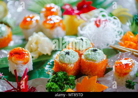 Un sacco di sushi rotoli con vari ripieni. Colpo di cotto giapponese classico cibo servito su ghiaccio. Immagine di sfondo Foto Stock