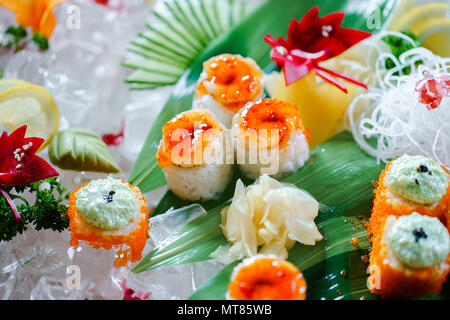 Un sacco di sushi rotoli con vari ripieni. Colpo di cotto giapponese classico cibo servito su ghiaccio. Immagine di sfondo Foto Stock
