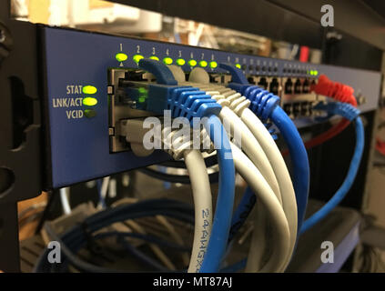 Bianco blu e arancione cavo di rete appendere fuori sulla parte anteriore di un hotel communications server rack Foto Stock