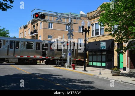 La linea marrone L-treno attraversa il Rockwell Ave. quartiere degli affari a livello della strada in Chicago's Ravenswood Giardini quartiere. Foto Stock