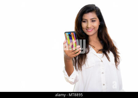 Studio shot di giovani felici persiano di donna sorridente mentre si utilizza il mob Foto Stock