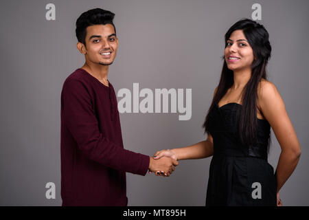 Giovani indiani l uomo e la giovane donna indiana insieme contro il grigio ba Foto Stock