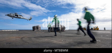 170715-N-OY799-487 CORAL SEA (Luglio 15, 2017) marinai di transito per cancellare l'area di atterraggio come un MH-60S Sea Hawk, dall'isola dei Cavalieri di elicottero di mare squadrone di combattimento (HSC) 25, termina la erogazione di pallet dal militare Sealift il comando di carichi secchi e munizioni nave USNS Charles Drew (T-AKE 10) per la Marina Militare è distribuita portaerei USS Ronald Reagan (CVN 76), come parte di un rifornimento in mare durante il talismano di Saber 2017. Talismano Saber è un realistico e stimolante esercizio che porta i membri del servizio più vicino e migliora sia negli Stati Uniti e in Australia la capacità di lavorare a livello bilaterale a Foto Stock