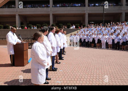 Esercito Col. (Dr) Jeffrey Hutchinson (sinistra), professore associato e deliberando sedia del Dipartimento di Pediatria presso il F. Edward Hebert School of Medicine, servizi in uniforme Università di Scienze della Salute di Bethesda, Md., offre commento alla scuola annuale del rivestimento bianco cerimonia, 11 maggio 2018. I membri di facoltà dalla scuola di Hebert di medicina in stand by per aiutare più di 170 del primo anno gli studenti medici don il rivestimento tradizionale, che simboleggia la transizione al servizio di cliniche e di assistenza al paziente. Foto Stock