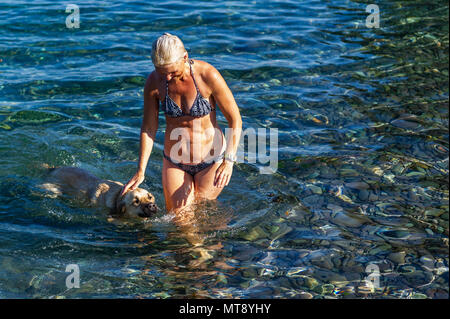 Schull, Irlanda. 28 Maggio, 2018. Una donna e il suo cane giocare in acqua in Schull su un blisteringly giornata calda in Schull. Met Éireann ha previsto una calda serata con sole nebuloso e la doccia dispari con bassi di 10 a 14 C. Credit: Andy Gibson/Alamy Live News. Foto Stock