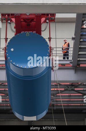 17 maggio 2018, Biblis, Germania: utilizzando un heavy-duty, gru di sollevamento dei lavoratori un blu container Castor all'interno di uno dei blocchi dei reattori di Biblis Centrale Nucleare. Lì, lo speciale contenitore viene riempito di acqua del serbatoio del reattore con gli elementi di combustibile, per essere poi portato in uno stoccaggio intermedio sui motivi della centrale nucleare. Dopo la fase di tedesco-del nucleare, l'impianto di alimentazione in Biblis saranno gradualmente smantellato. Foto: Boris Roessler/dpa Foto Stock