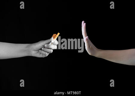 Celebra la Giornata Mondiale senza tabacco, 31 maggio. Basta dire no a smettere di fumare. Close up man mano sigaretta rifiuta di offrire su sfondo nero. Foto Stock