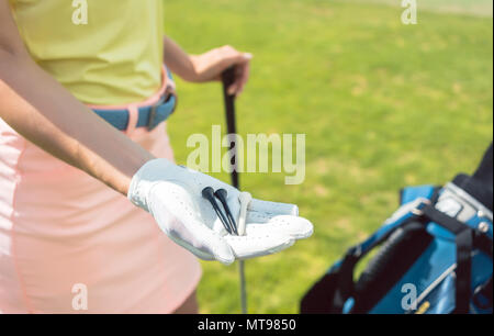 Close-up della mano di una donna con tre tees su un campo da golf Foto Stock