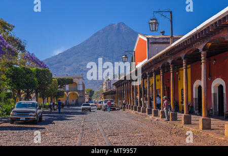 A Ciudad de Guatemala, Aprile 25, 2018: lapidato apvement street e la gente camminare e godere la splendida giornata soleggiata della città di Antigua e il vulcano Agua in background Guatemala Foto Stock