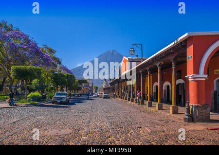 A Ciudad de Guatemala, Aprile 25, 2018: lapidato apvement street e la gente camminare e godere la splendida giornata soleggiata della città di Antigua e il vulcano Agua in background Guatemala Foto Stock