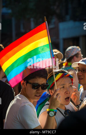 NEW YORK CITY - Giugno 25, 2017: amici asiatici wave arcobaleno e noi le bandiere sugli spalti dell annuale Pride Parade in Greenwich Village Foto Stock