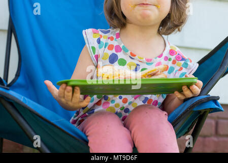 Un bambino ragazza con un panino di prosciutto al di fuori Foto Stock