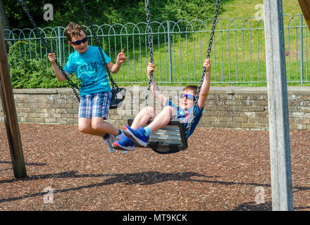 Giovani Fratelli giocare sulle altalene nel parco giochi per bambini in Bachelors Acro in Windsor, Regno Unito. Foto Stock