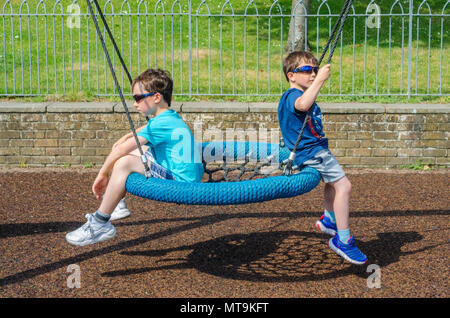 Giovani Fratelli giocare sulle altalene nel parco giochi per bambini in Bachelors Acro in Windsor, Regno Unito. Foto Stock