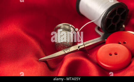 Accessori per il cucito su uno sfondo di stoffa rossa Foto Stock