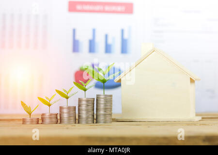 Staced di denaro e di albero che cresce e casa su un foglio di carta millimetrata sfondo, concetto come salvare, finanza, account, vendita e acquisto di casa Foto Stock