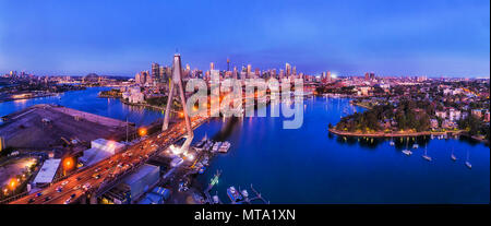 Blu scuro Periodo di tempo dopo il tramonto sulla città di Sydney CBD lungo ANZAC ponte sopra il porto di baie e calette nel panorama dell'antenna. Foto Stock