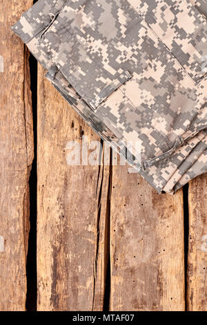 Piegate il camuffamento pantaloni di pattern su pavimento di legno. Immagine ritagliata, piatto di laici che, vista dall'alto. Foto Stock