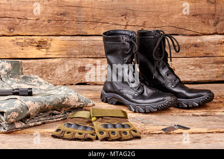 Uniforme militare impostato su sfondo di legno. Stivali neri, guanti e indumenti. Foto Stock