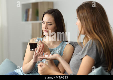 Donna di rigetto di zucchero per il caffè seduta su un divano nel salotto di casa Foto Stock