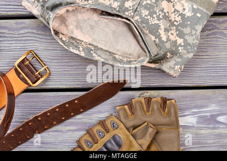 Abbigliamento Militare, cintura arancione e guanti senza dita. Scrivania in legno sfondo. Foto Stock