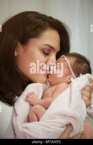 Madre ispanica tenere bambino neonato con gli occhi chiusi Foto Stock