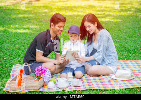 Asian teen teching famiglia istruzione al capretto felice vacanza momento picnic nel parco verde Foto Stock