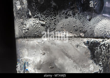 Acqua ghiacciata in un bicchiere di vetro. Vetro con acqua ghiacciata e cubetti di ghiaccio. Il raffreddamento in un giorno caldo concetto. Foto Stock