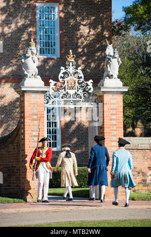 Colonial Williamsburg, il Palazzo del Governatore Gate. Un redcoat guard consente l'entrata di tre colonials. Rievocazione storica e storia viva, Williamsburg, VA. Foto Stock