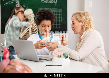 Grave giovane ragazzo in possesso di un modello del cervello Foto Stock