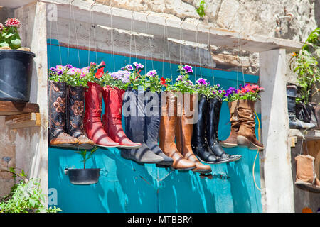 Stivali vecchi usati come vasi di fiori sulla porta di ingresso di una casa, Israele Foto Stock