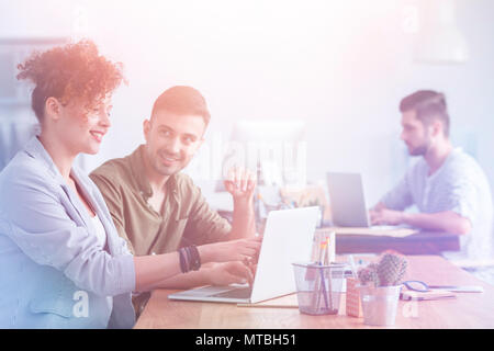 Mulatto e caucasici dipendenti discutono tra di loro in un ufficio moderno Foto Stock