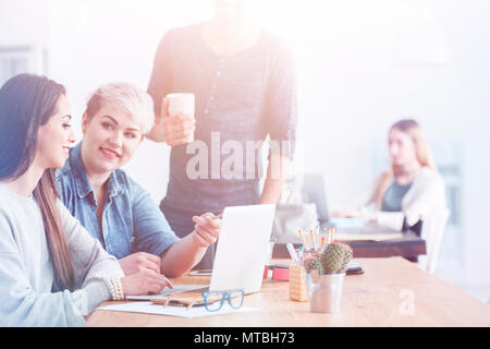 Due colleghi caucasica discutendo un progetto di lavoro utilizzando un computer portatile Foto Stock