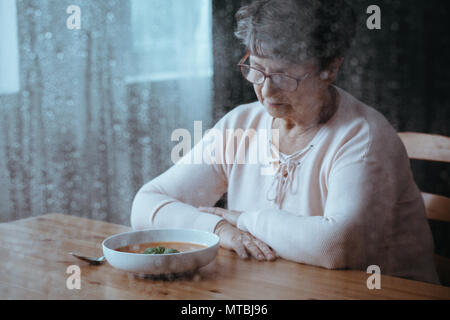 Triste, senior donna avente la mancanza di appetito Foto Stock
