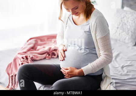 Allegra donna incinta toccando il suo stomaco Foto Stock