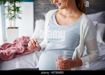 Giovane donna incinta prendendo capsule Foto Stock