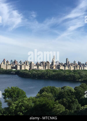 Alberi e stagno nel Central Park di New York City e la Quinta Avenue edifici di appartamenti Foto Stock